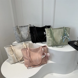 Minimalist large tote bag with silk scarf detail in multiple colors on a podium