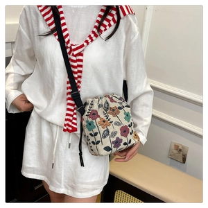 Floral canvas drawstring bucket bag with adjustable shoulder strap shown on model