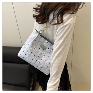 Detail of light blue quilted tote with bow print and golden metal ring strap attachment
