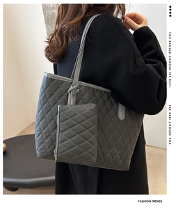 Detail view of large dark grey quilted tote bag with matching pouch shown on a model