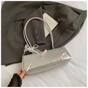 Detail of silver baguette bag with pink bows and lace pearls on grey blazer background