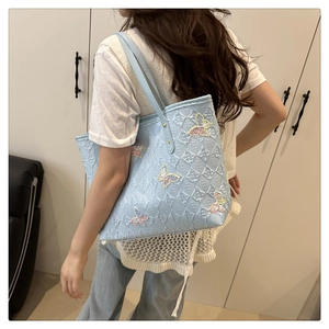 Detail of light blue tote bag with E-letter quilting and colorful butterfly embroidery