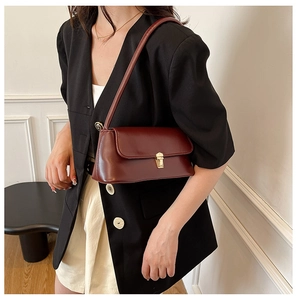 Detail of dark red vintage baguette bag featuring smooth leather and gold lock buckle