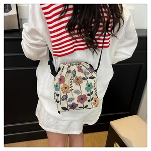 Floral drawstring bucket bag with adjustable black strap shown on a female model
