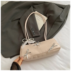 Detail of cream PU leather shoulder bag with silver bows and pearl lace charm