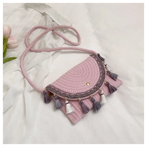 Detailed shot of pink woven crossbody bag featuring purple fringes and magnetic closure