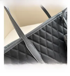 Close-up of diamond quilted stitching and sturdy handles on the dark grey tote bag