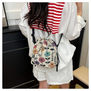 Detail of drawstring bucket bag with colorful floral print and adjustable black straps