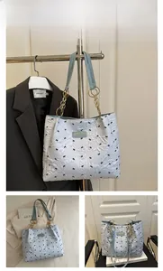 Detail view of light blue floral tote bag with cute black bow patterns and chain strap