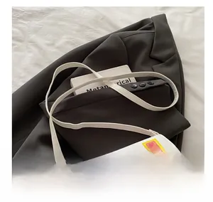Détail de la bandoulière blanche avec boucle en métal doré sur un sac selle au design moderne