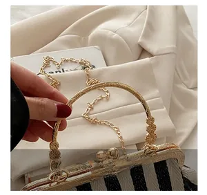Detailed shot of engraved gold metal handle and stripe pattern on shell bag