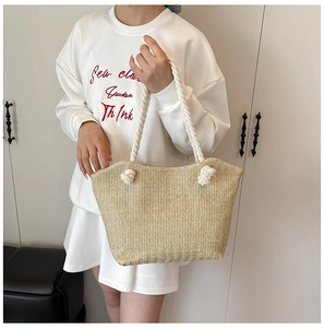 Detail of light beige straw tote bag featuring white cotton rope handles and woven texture
