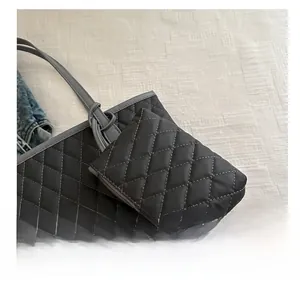 Detail of a black quilted mini accessory bag with zipper hanging on a tote bag
