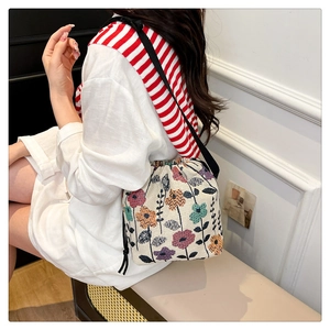 Close-up of floral canvas bucket bag with drawstring closure and black strap detail