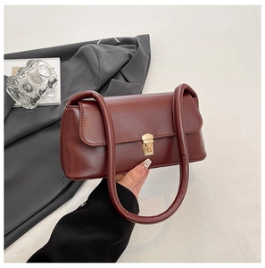 Detailed view of the dark burgundy baguette bag with a metallic gold buckle closure
