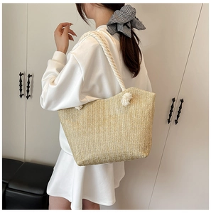 Detail of straw tote bag showing beige herringbone weave and white rope handles