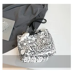Detail of white graffiti canvas tote with black leather chain strap and cloud charm