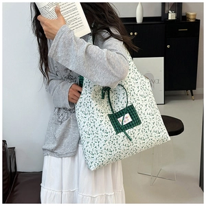 Détail du sac en toile fleurie avec poche avant à carreaux et étiquette tissée