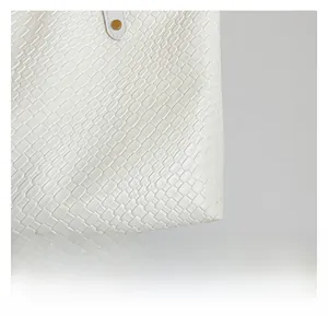 Macro shot of white textured leather material and golden metal rivets on shoulder bag