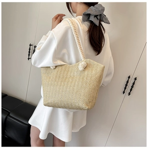 Close-up of beige woven tote bag with white rope handles and metal eyelets