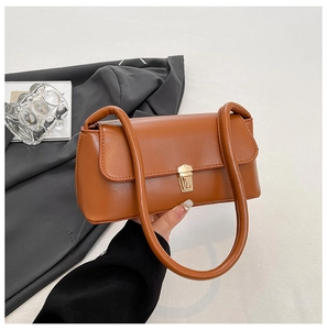 Detail view of brown leather baguette bag with dual tubular straps and gold square lock
