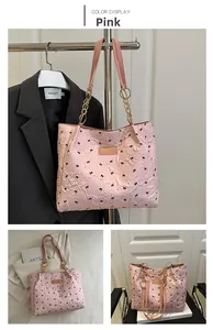 Detail of pink tote bag with black bow embroidery and golden chain straps