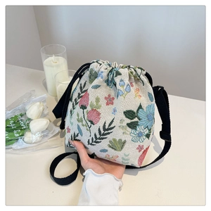Detailed close-up of retro floral embroidery on fabric drawstring bucket shoulder bag