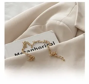 Macro shot of gold-plated metal chain strap on minimalist beige blazer and book