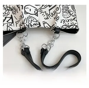Close-up of graffiti print canvas tote bag with black leather and metal chain straps