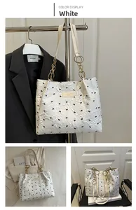 Detail of white embossed floral tote bag with black bows and gold chain strap