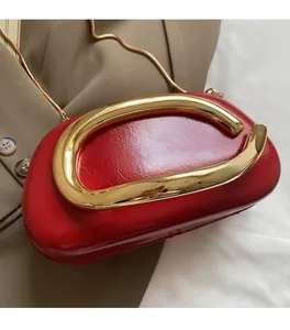 Macro detail of red glossy leather shoulder bag with large gold C-shaped metal handle