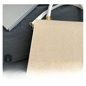 Detail of woven fabric texture and white leather trim with gold metal hardware on handbag