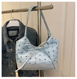 Close-up of light blue bucket bag with black rabbit pattern and ribbon bow detail