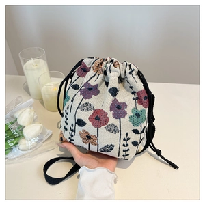 Detail of floral tapestry bucket bag with woven patterns and black drawstring closure