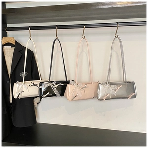 Detail of glossy patent leather shoulder bags featuring lace bows and pearl charms