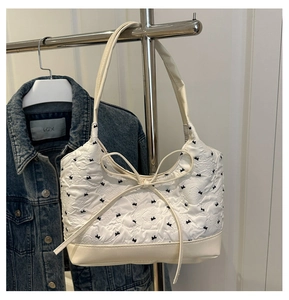 Detail of white bucket bag featuring floral embossing and black bow embroidery textures