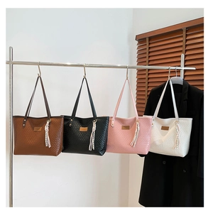 Detail view of woven leather tote bags in four colors with fringe tassel accents