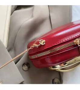 Close-up of red glossy evening bag featuring gold metal handle and polished chain strap
