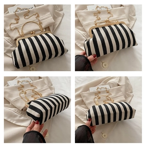 Detail view of black and white striped handbag with golden metal handle and chain strap