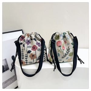 Detail of floral tapestry drawstring bucket bags with adjustable straps on a white stand