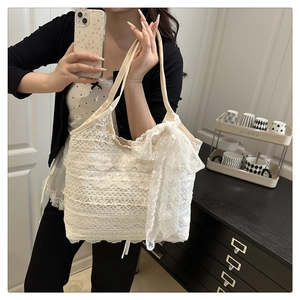 Detailed view of white lace tote bag featuring elegant layered ruffles and a large bow detail