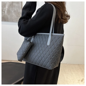 Detail view of large quilted tote bag in grey with matching zipper pouch and shoulder strap