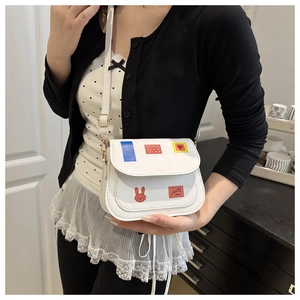 Close-up of white crossbody bag with colorful patches and golden hardware detail
