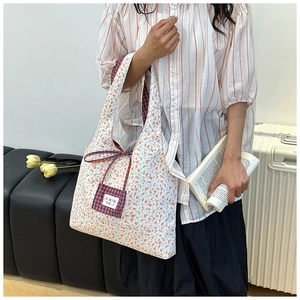 Détail du sac cabas en toile fleurie avec poche à carreaux orange et étiquette