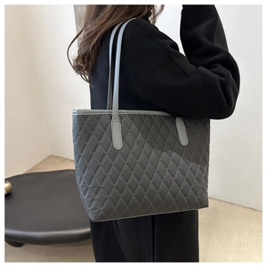 Detail of grey quilted tote bag showing diamond stitch pattern and shoulder strap texture