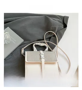 Detail of off-white crossbody bag featuring metallic handle and heart-shaped lock detail