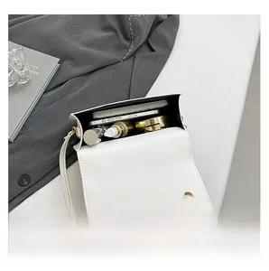 Internal view of white leather saddle bag showing capacity for phone and cosmetics