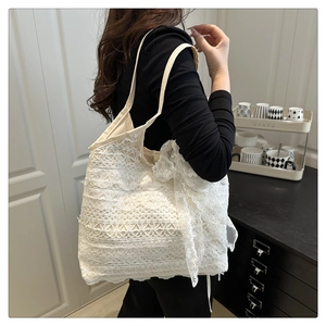 Detailed close-up of a white floral lace tote bag featuring an elegant lace bow decoration