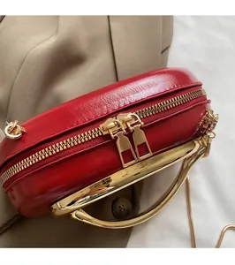 Detail of red leather evening bag with smooth gold zippers and metallic chain strap