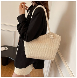 Detail of a large straw tote bag with decorative thick rope handles for summer style